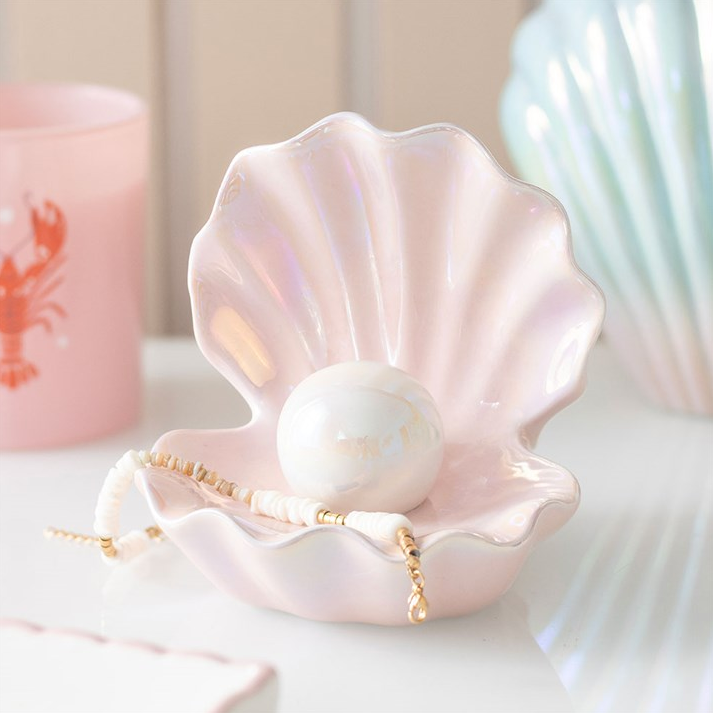 Pink shell with a pearl and necklace on a white surface 