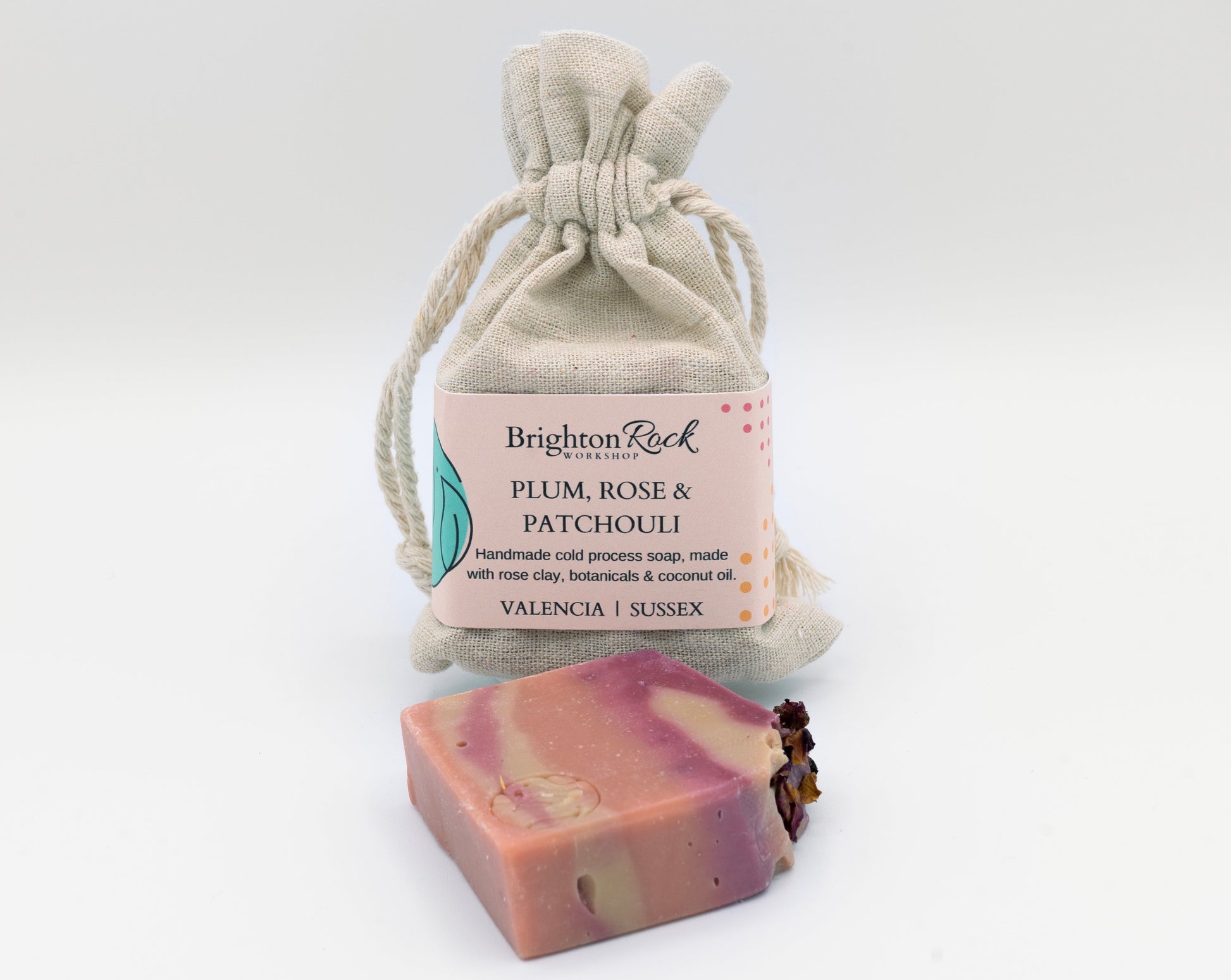 Plum, rose & patchouli scanted natural soap in cotton drawstring bag with Brighton Rock Workshop label. Handmade in Spain. Made with natural skin-loving ingredients. Olive oil, shea butter, coconut oil, cocoa butter, rose clay and botanical ingredients. eco friendly and sustainable